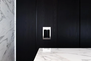 Detalle de una cocina con madera oscura y marmol blanco y gris